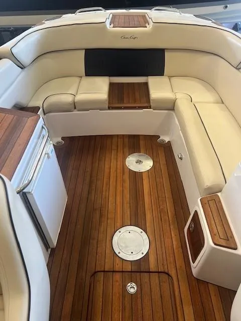 Slide: The Image of 2004 Chris-Craft Corsair 25 interior with wooden flooring and white cushioned seating. - 15