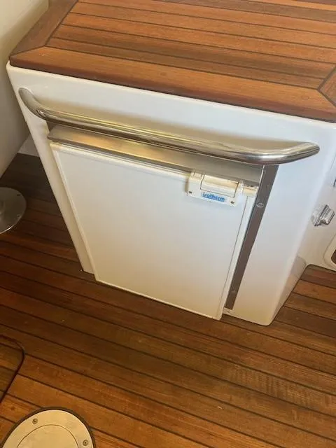 Slide: The Image of 2004 Chris-Craft Corsair 25 boat interior with wooden flooring and built-in refrigerator. - 17