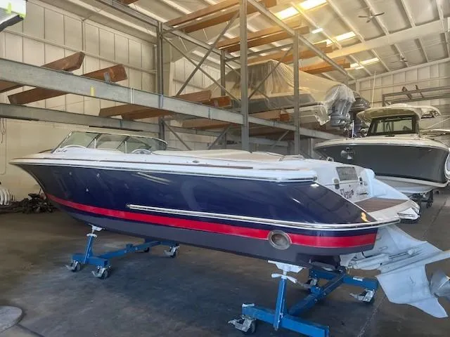 Slide: The Image of 2004 Chris-Craft Corsair 25 boat in storage, blue and red hull, indoor warehouse setting. - 5