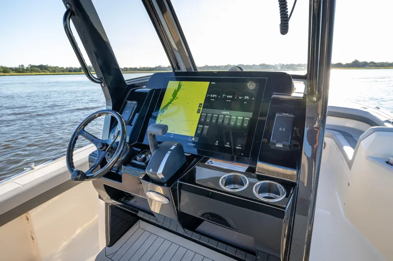 Slide: The Image of 2026 Scout 281 X Signature Edition boat dashboard with advanced navigation system on a calm waterway. - 12