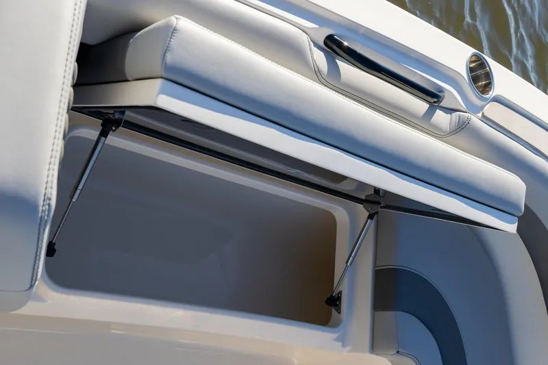 Slide: The Image of 2026 Scout 281 X Signature Edition boat storage compartment with cushioned seat and hydraulic support. - 7