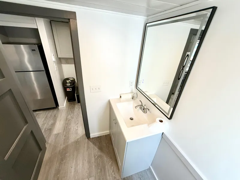 Slide: The Image of Modern bathroom with sink, large mirror, and adjacent kitchen area in a 1987 Three Buoys 5014. - 17