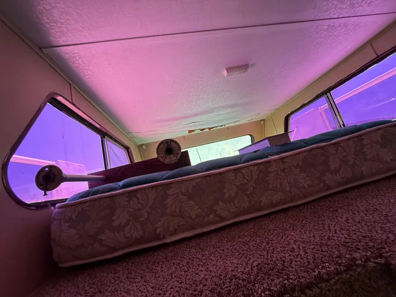 Slide: The Image of Interior of 1987 Three Buoys 5014 boat with mattress and purple-tinted windows. - 24