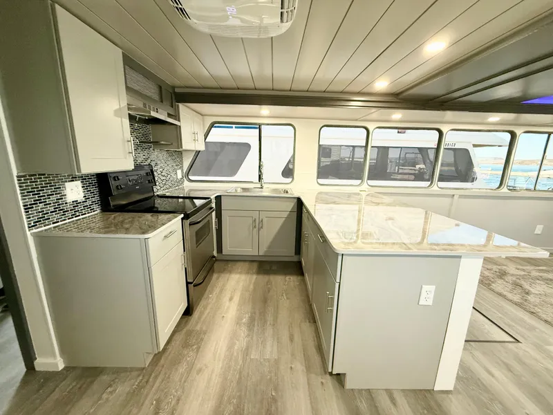 Slide: The Image of Modern kitchen interior on 1987 Three Buoys 5014 houseboat with sleek countertops and ample natural light. - 8