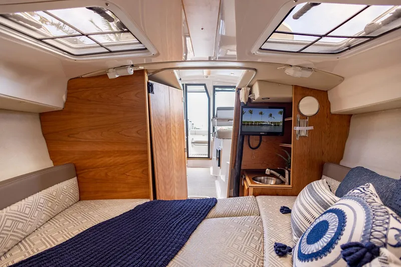 Slide: The Image of Manufacturer Provided Image: Interior of 2022 Cutwater C-248 Coupe boat with cozy bed, TV, and wooden accents. - 12