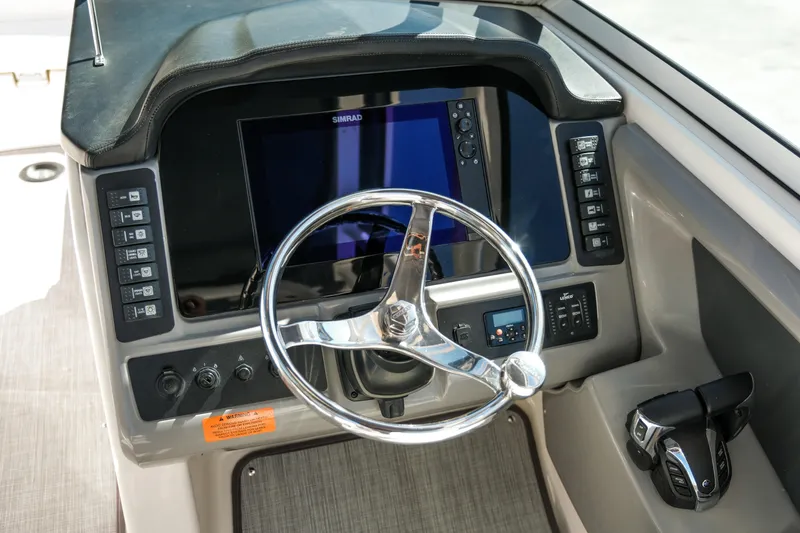 Slide: The Image of 2022 Robalo R247 DC boat dashboard with steering wheel and control panel. - 11