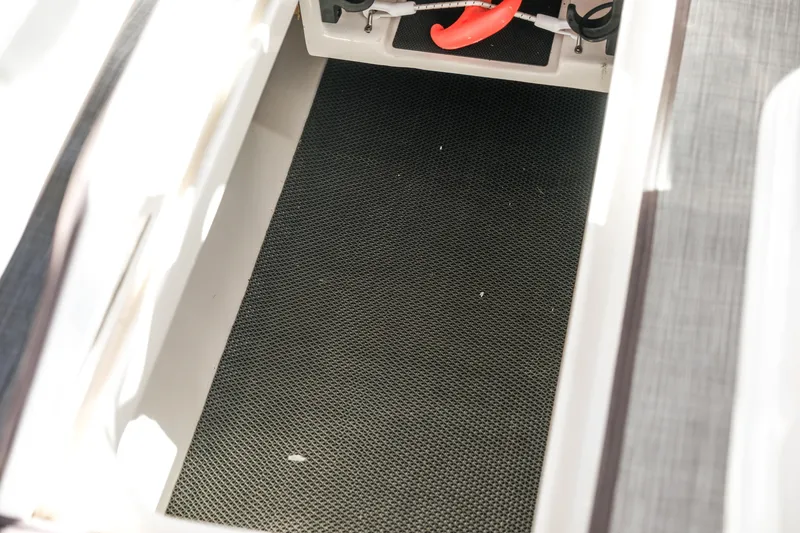 Slide: The Image of Storage compartment of 2022 Robalo R247 DC boat, featuring a textured black mat. - 15