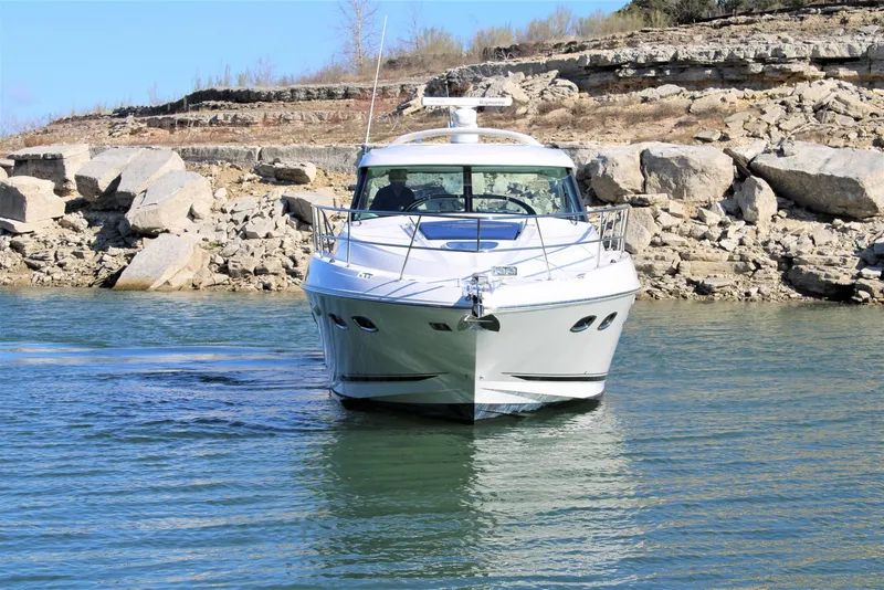 Slide: The Image of 2012 Sea Ray 450 Sundancer yacht cruising near rocky shoreline. - 11