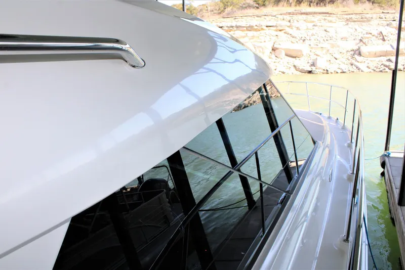Slide: The Image of 2012 Sea Ray 450 Sundancer yacht docked by rocky shoreline. - 31