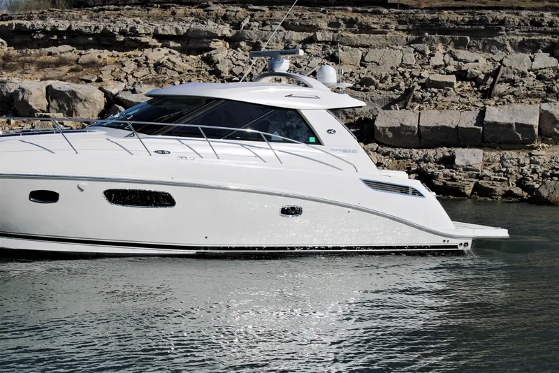 Slide: The Image of 2012 Sea Ray 450 Sundancer yacht cruising near rocky shoreline. - 4