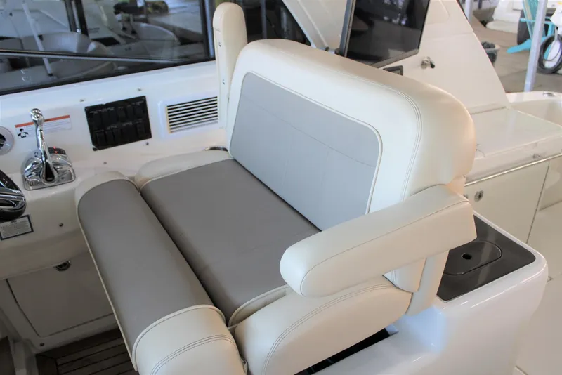 Slide: The Image of Captain's seat on a 2012 Sea Ray 450 Sundancer yacht, featuring luxurious white and gray upholstery. - 41