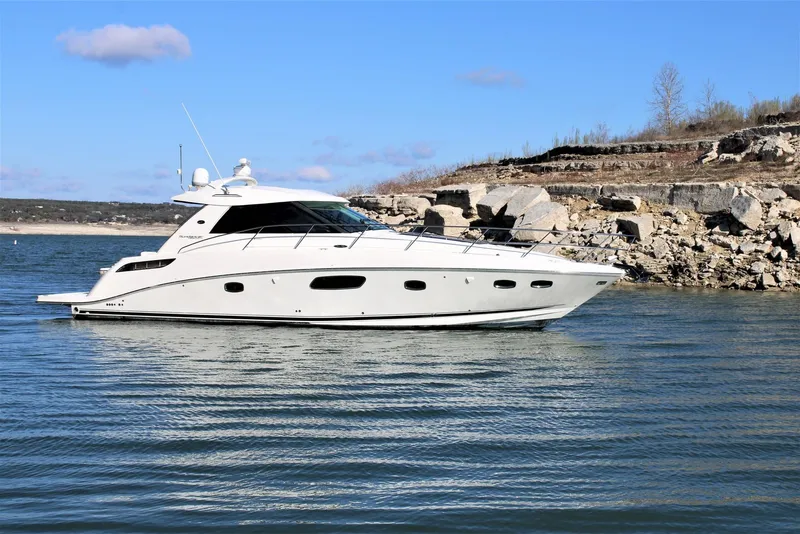 Slide: The Image of 2012 Sea Ray 450 Sundancer yacht on calm water near rocky shoreline. - 7