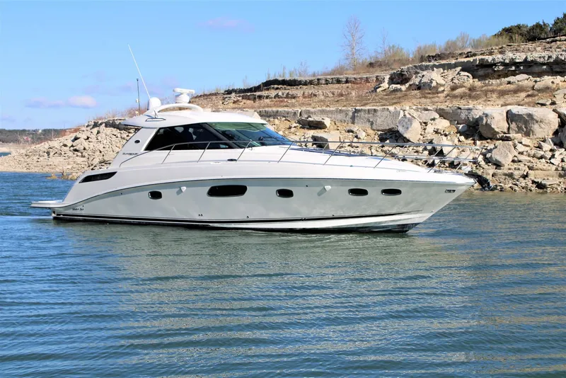 Slide: The Image of 2012 Sea Ray 450 Sundancer yacht cruising on a calm lake near rocky shoreline. - 8
