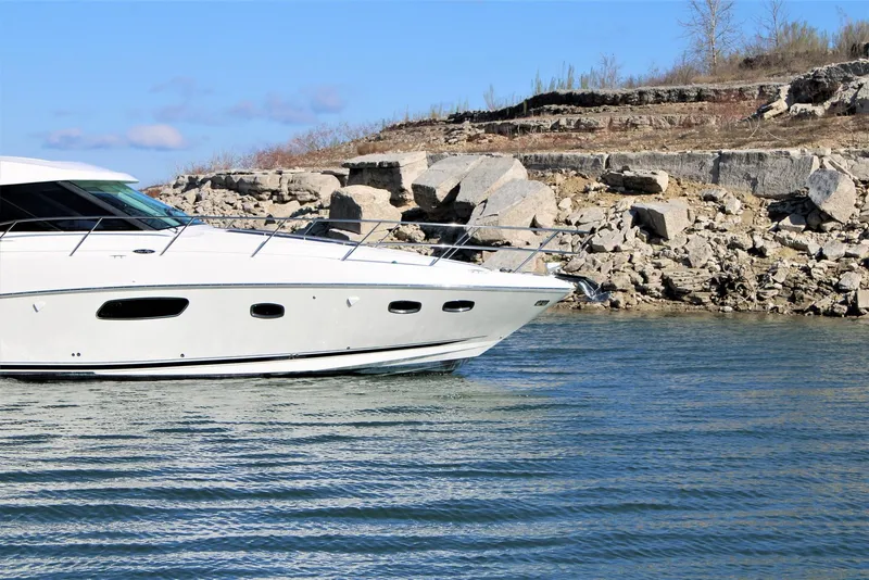Slide: The Image of Sea Ray 450 Sundancer 2012 yacht cruising near rocky shoreline under clear blue sky. - 9