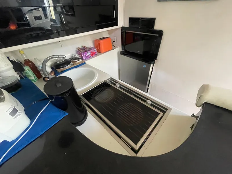 Slide: The Image of Compact kitchen area in a 1988 Californian express cruiser, featuring a sink, stove, and mini fridge. - 10
