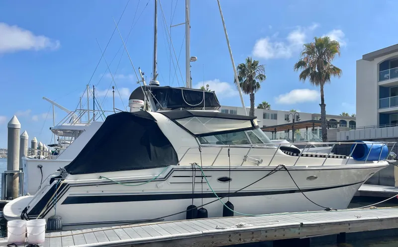 Slide: The Image of 1988 Californian express cruiser docked at marina with palm trees and buildings in background. - 34