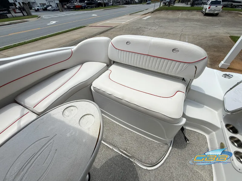 Slide: The Image of 2006 Crownline 260 EX boat interior with white seating and red accents, parked on pavement. - 13