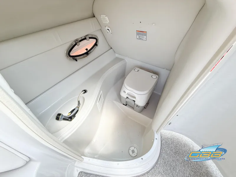 Slide: The Image of 2006 Crownline 260 EX boat interior with compact marine toilet and porthole window. - 27