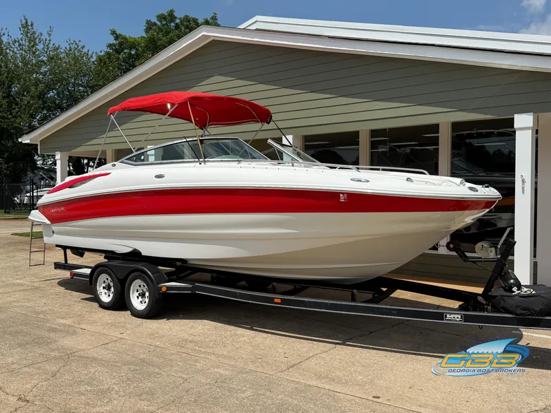 Slide: The Image of 2006 Crownline 260 EX boat with red canopy on trailer, parked outside a building. - 3