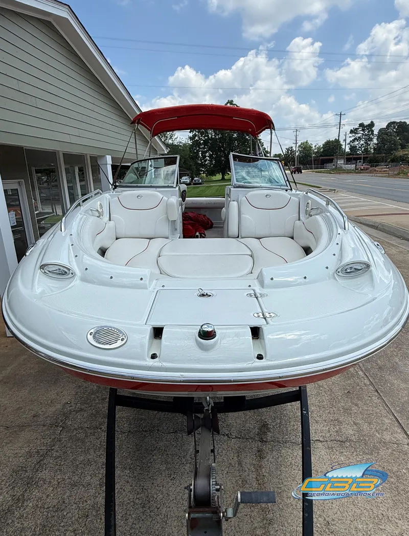 Slide: The Image of 2006 Crownline 260 EX boat with red canopy, parked on a trailer, under a partly cloudy sky. - 8