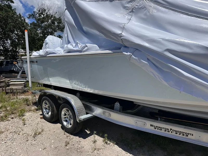 Slide: The Image of 2025 Sportsman Masters 247OE Bay Boat on trailer, partially covered, outdoors. - 2