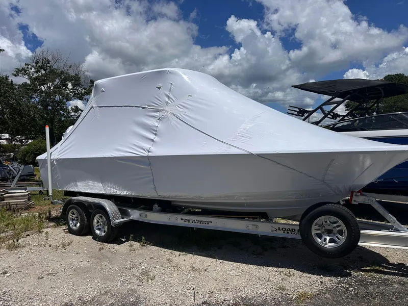 Slide: The Image of 2025 Sportsman Masters 247OE Bay Boat covered on trailer under cloudy sky. - 4