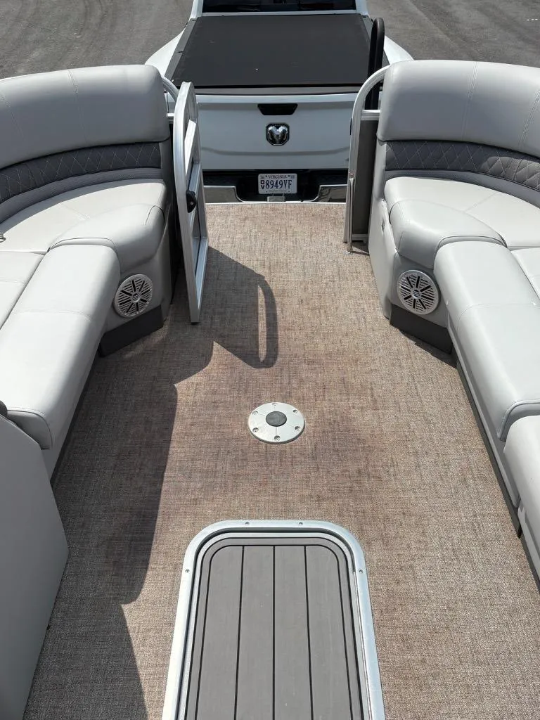 Slide: The Image of 2022 Ranger Reata 223C boat interior with plush seating and speakers, parked near a truck. - 10