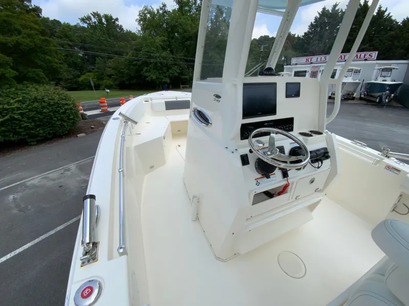 Slide: The Image of 2023 Cobia 240 Center Console boat with steering wheel and control panel, parked outdoors. - 21