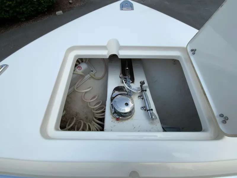 Slide: The Image of 2023 Cobia 240 Center Console anchor storage compartment with coiled rope and winch. - 25