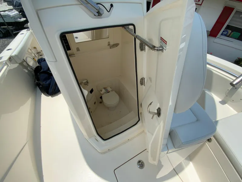 Slide: The Image of 2023 Cobia 240 Center Console boat with open cabin door revealing interior toilet. - 30