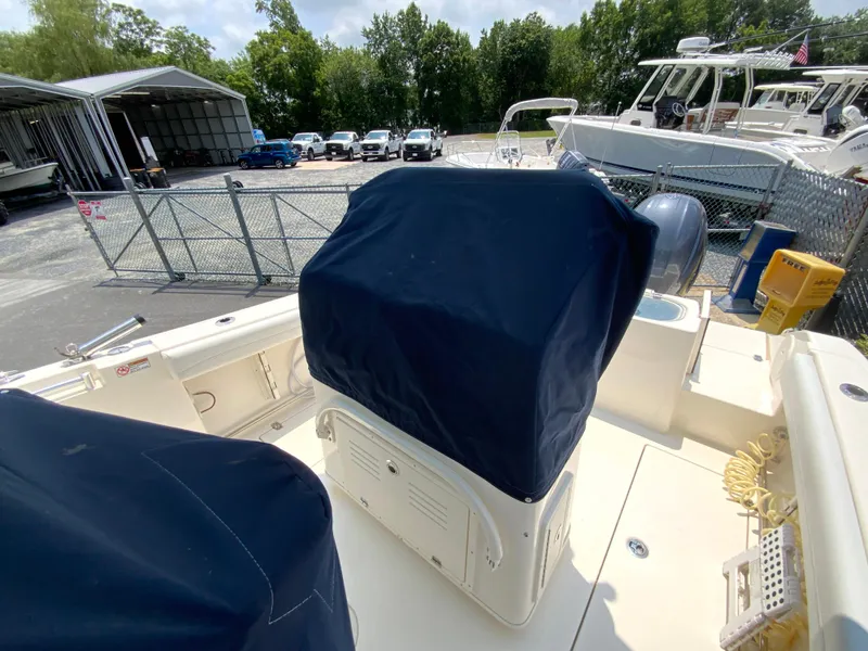 Slide: The Image of 2023 Cobia 240 Center Console boat with covered console, parked near other boats and vehicles. - 35