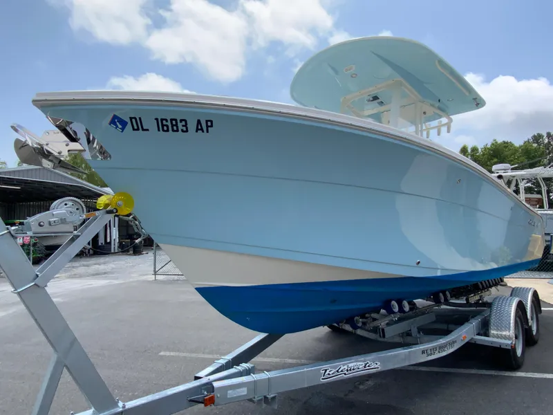 Slide: The Image of 2023 Cobia 240 Center Console boat on trailer, parked outdoors under blue sky. - 5