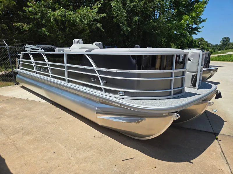 Slide: The Image of 2025 Trifecta 24 UL LET2.75 pontoon boat parked on concrete, surrounded by trees. - 4