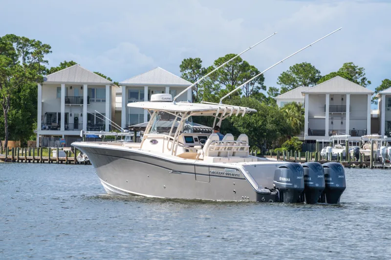 Slide: The Image of 2017 Grady-White 336 Canyon boat with triple Yamaha engines on a calm waterfront. - 12