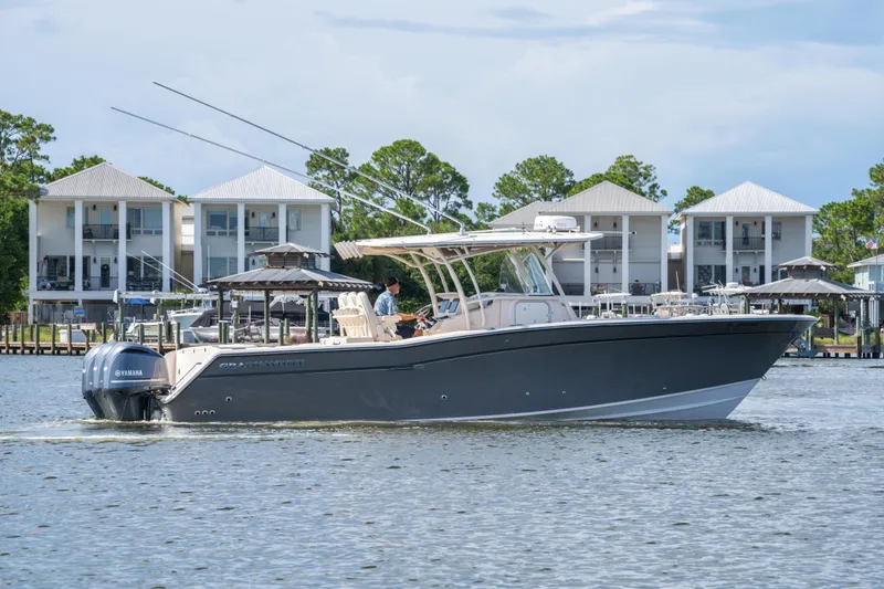 Slide: The Image of 2017 Grady-White 336 Canyon boat cruising on a calm waterway with waterfront homes in the background. - 16