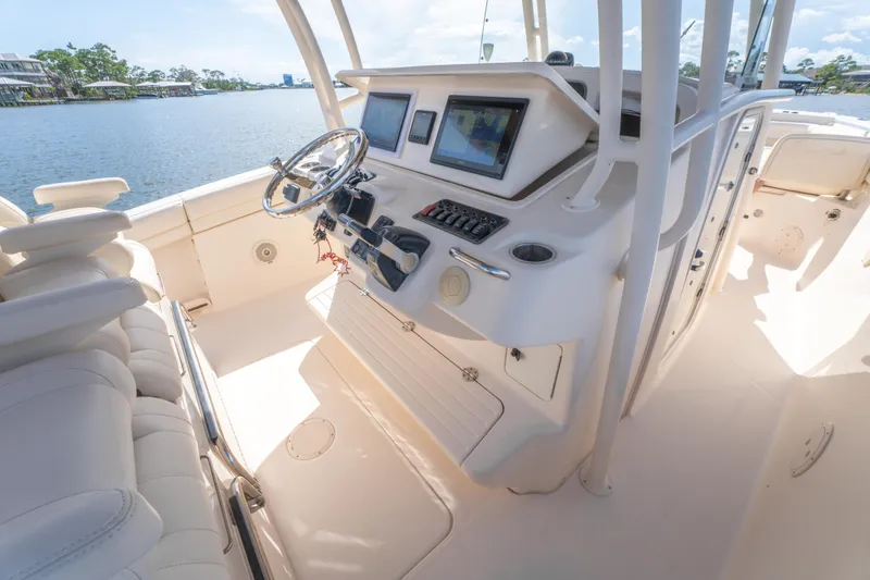 Slide: The Image of 2017 Grady-White 336 Canyon boat cockpit with steering wheel and navigation screens. - 25
