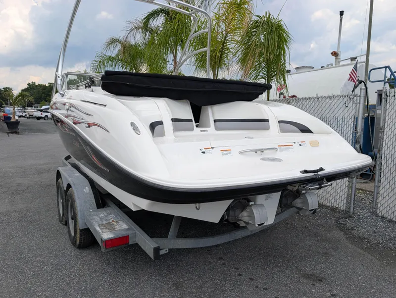 Slide: The Image of 2004 Yamaha Boats AR230 HO on trailer, parked near palm trees and fence. - 6