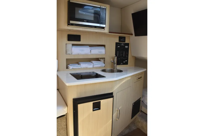 Slide: The Image of 2026 Regal 26 XO boat interior kitchen with microwave, sink, and storage. - 37