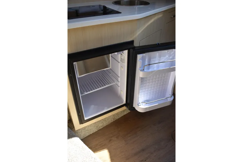 Slide: The Image of Open mini fridge in 2026 Regal 26 XO boat interior, showcasing compact storage space. - 38