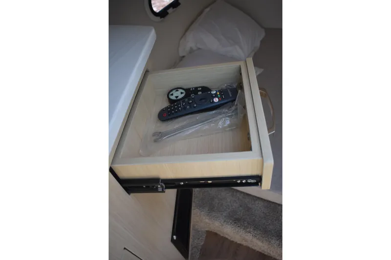 Slide: The Image of Open drawer in 2026 Regal 26 XO boat cabin with remote control inside. - 42