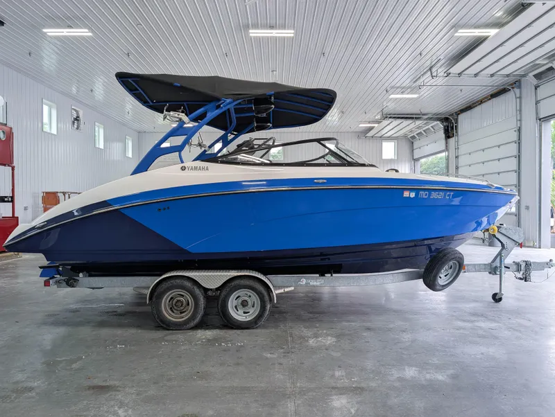 Slide: The Image of 2019 Yamaha Boats 242X E-Series in a garage, blue and white design on trailer. - 1