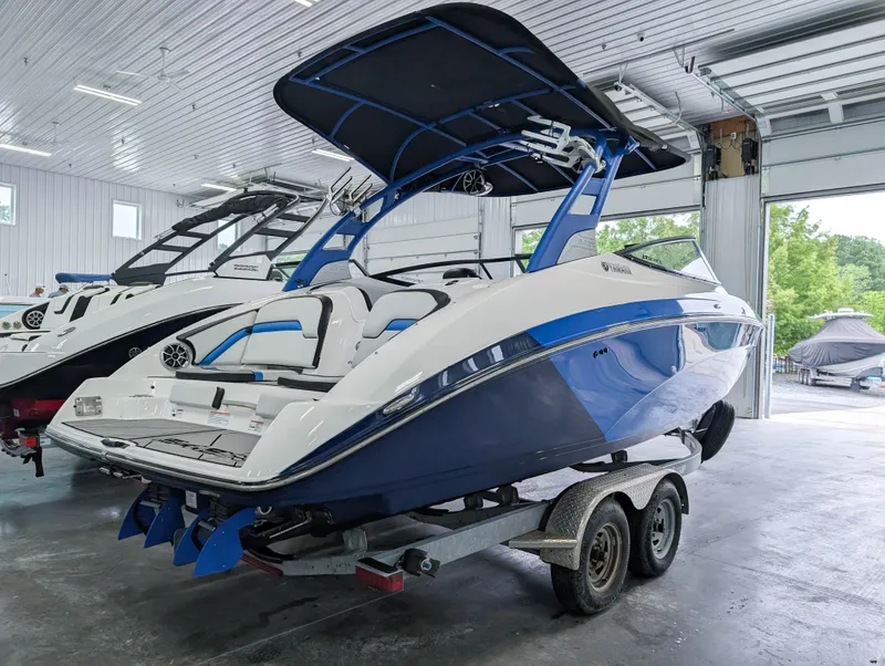 Slide: The Image of 2019 Yamaha Boats 242X E-Series in showroom, blue and white design, on trailer. - 10
