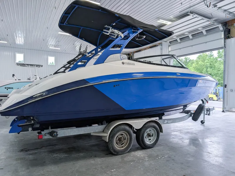 Slide: The Image of 2019 Yamaha Boats 242X E-Series in a garage, blue and white design on trailer. - 11