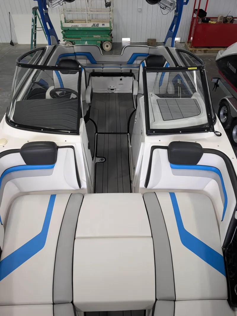 Slide: The Image of 2019 Yamaha Boats 242X E-Series interior with blue and gray seating, in a showroom. - 24