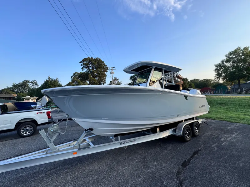 Slide: The Image of 2025 Blackfin 272 CC boat on trailer at sunset, parked on asphalt. - 0