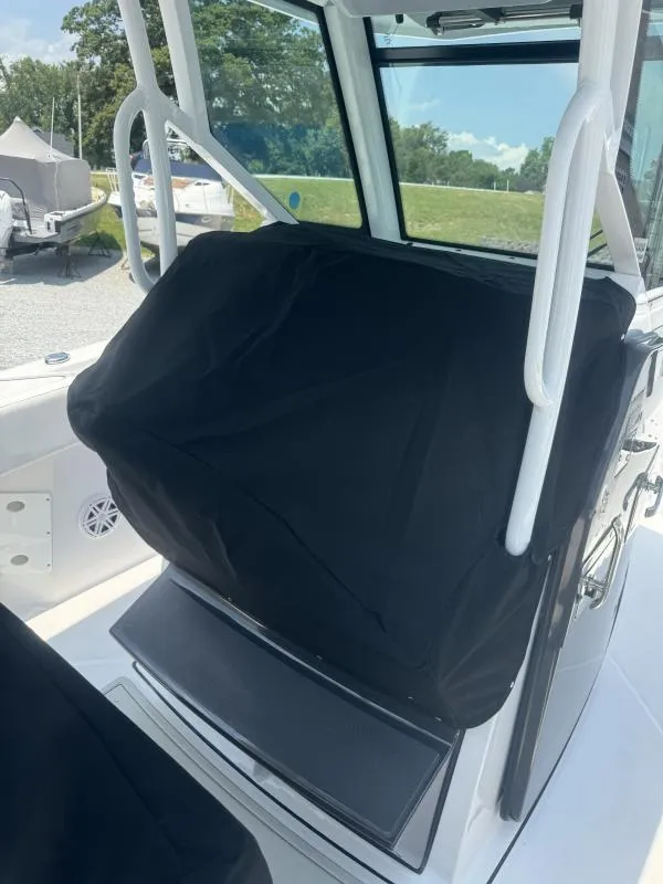 Slide: The Image of 2025 Blackfin 272 CC boat console with protective cover, docked outdoors. - 12