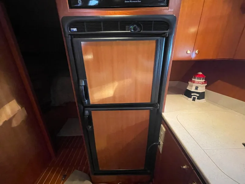 Slide: The Image of 2005 Novatec 48 Cockpit Motor Yacht kitchen with wooden cabinetry and compact refrigerator. - 51