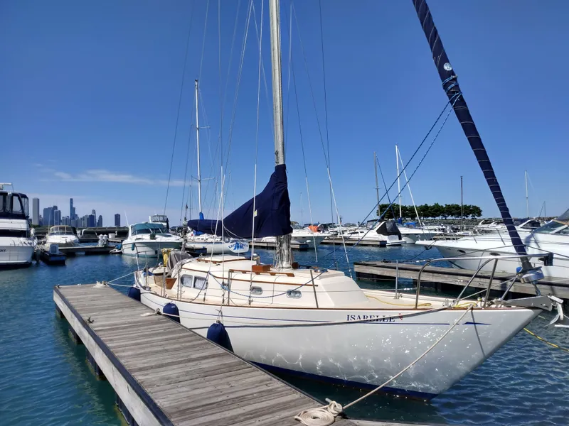 The Image of 1969 Chris-Craft Apache 37 sailboat docked in marina with city skyline background. - 0