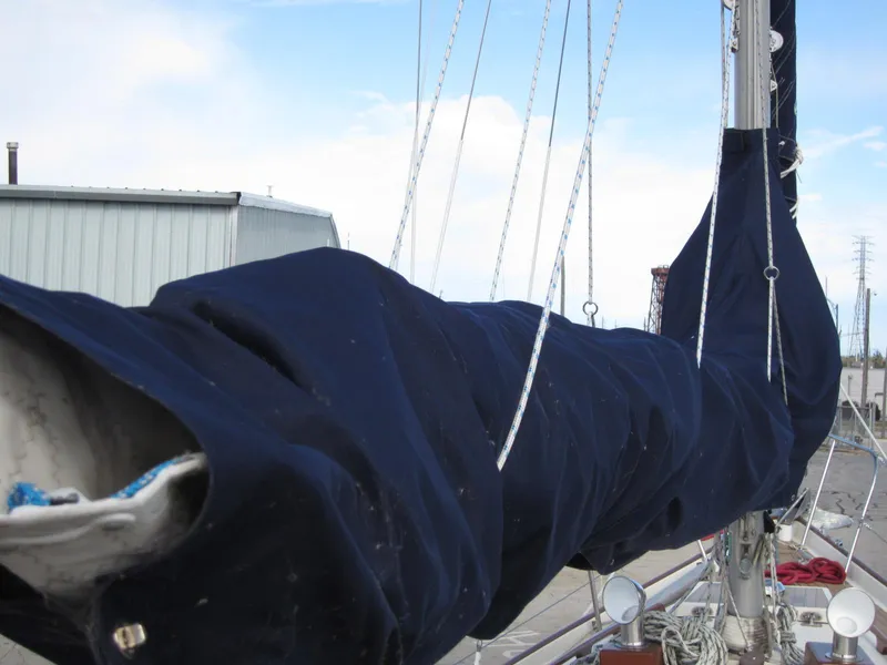 Slide: The Image of 1969 Chris-Craft Apache 37 sailboat with covered boom and rigging, docked near a warehouse. - 12