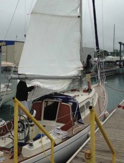 Slide: The Image of 1969 Chris-Craft Apache 37 sailboat docked, with two people adjusting sails. - 13